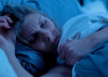 Eine Frau schläft mit gestresstem Gesichtsausdruck.
