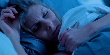 Eine Frau schläft mit gestresstem Gesichtsausdruck.