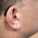 Ein Hörgerät hinter dem Ohr eines Mannes.