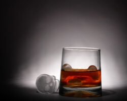 Bild von einem Glas Alkohol mit einen Totenkopf aus Eis daneben.