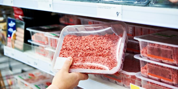Eine Person nimmt eine Packung Hackfleisch aus einem Regal im Supermarkt.