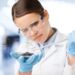 Eine Frau in Laborkleidung gibt mit einer Pipette eine Flüssigkeit in eine Petrischale.