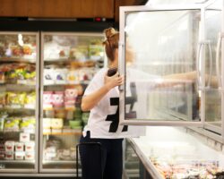 Frau wählt Tiefkühlkost aus einem Supermarkt-Gefrierschrank
