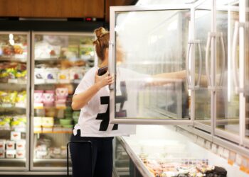 Frau wählt Tiefkühlkost aus einem Supermarkt-Gefrierschrank