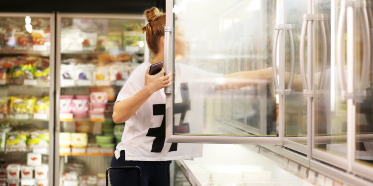 Frau wählt Tiefkühlkost aus einem Supermarkt-Gefrierschrank