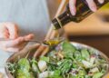 Frau gibt Speiseöl zu einem Salat