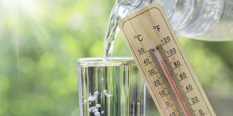 Ein Thermometer vor einem Glas in das Wasser geschüttet wird