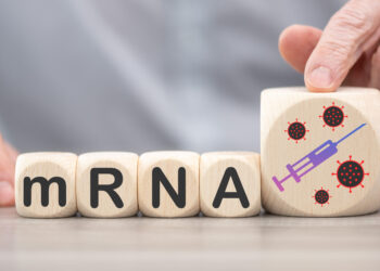 Holzbauklötze mit aufgedruckten Buchstaben bilden das Wort "mRNA".