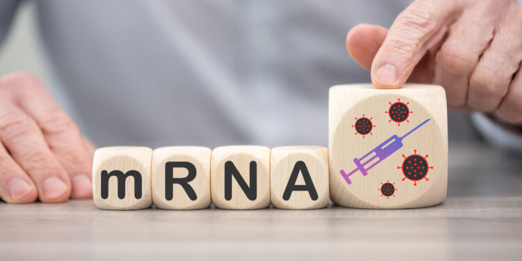 Holzbauklötze mit aufgedruckten Buchstaben bilden das Wort "mRNA".