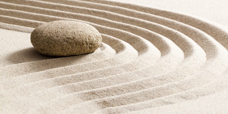Ein Stein liegt im Sand.