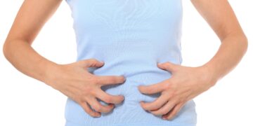 weibliche Person hält sich den Bauch