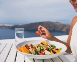 Restaurant woman eating salad luxury europe travel Santorini vacation. Healthy lifestyle people relaxing on Greece holidays.