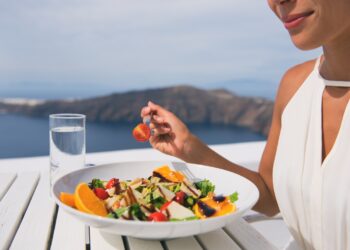 Restaurant woman eating salad luxury europe travel Santorini vacation. Healthy lifestyle people relaxing on Greece holidays.