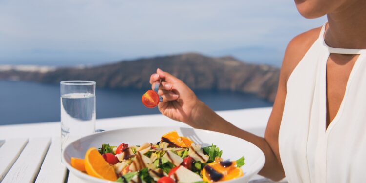 Restaurant woman eating salad luxury europe travel Santorini vacation. Healthy lifestyle people relaxing on Greece holidays.