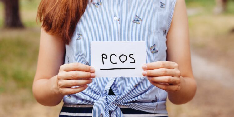 Frau hält einen Zettel mit der Aufschrift PCOS vor sich