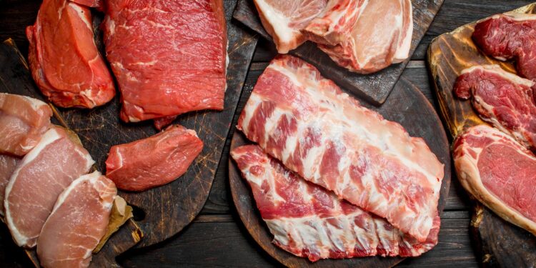 Verschiedene Sorten von rotem Fleisch liegen auf einer hölzernen Oberfläche.