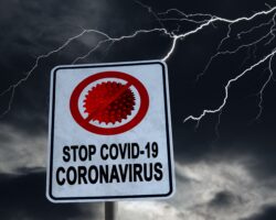 Auf einem Schild steht "STOP COVID-19". Im Hintergrund tobt ein Gewitter.