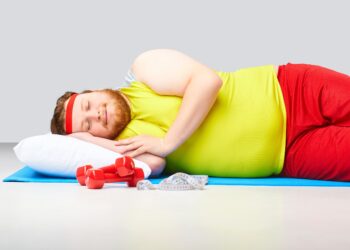 Ein Mann mit Übergewicht liegt auf einer Fitness-Matte und schläft.
