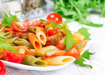 Ein Nudelsalat ist auf einem weißen Teller angerichtet.