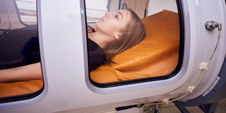 Frau liegt in Kabine für die hyperbare Sauerstofftherapie