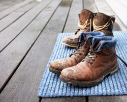 Schmutzige Stiefel stehen auf einem Fußabtreter.