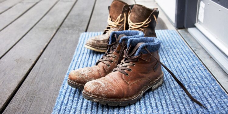 Schmutzige Stiefel stehen auf einem Fußabtreter.