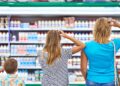 Zwei Frauen und ein kleiner Junge stehen vor einem Regal im Supermarkt.