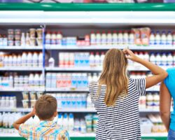 Zwei Frauen und ein kleiner Junge stehen vor einem Regal im Supermarkt.