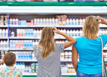 Zwei Frauen und ein kleiner Junge stehen vor einem Regal im Supermarkt.