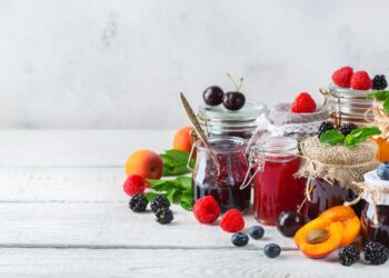 Verschiedene Gläser mit selbst gekochter Marmelade stehen auf einer weißen Oberfläche.