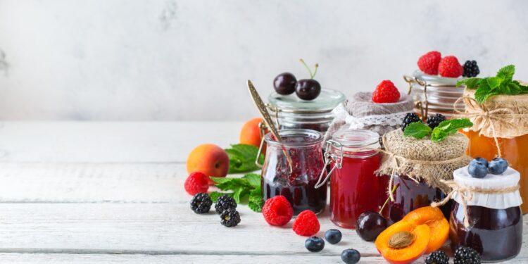 Verschiedene Gläser mit selbst gekochter Marmelade stehen auf einer weißen Oberfläche.