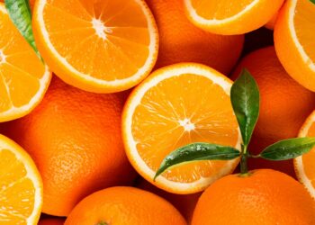 Ganze und halbierte Orangen und einige Orangenblätter