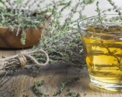 Glas mit Thymiantee und daneben ein Strauß Thymian