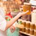 Eine Frau im Supermarkt hält ein Glas Marmelade in der Hand.