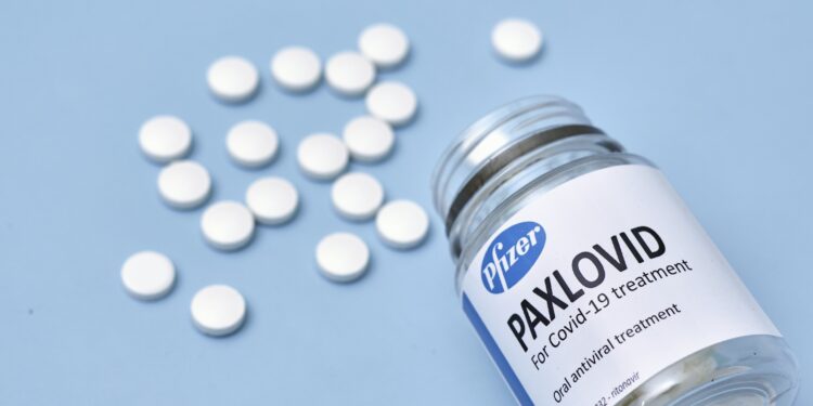 Eine Medikamenten-Verpackung mit der Aufschrift "PAXLOVID" liegt auf einem blauen Untergrund.