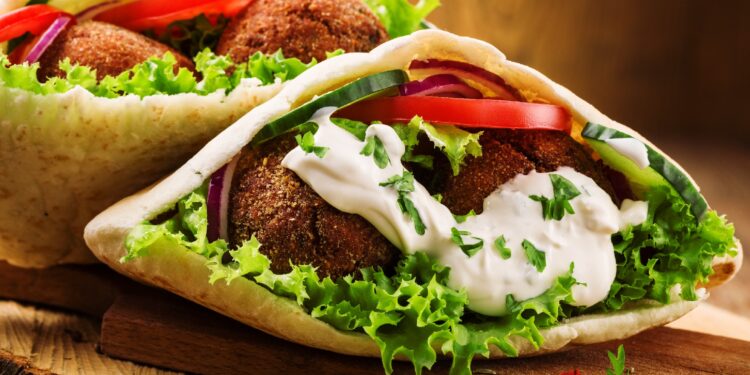 Zwei Falafel-Taschen sind auf einem Holzbrettchen angerichtet.