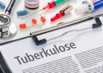Klemmbrett mit einem Zettel zu Tuberkulose neben diversen Medikamenten