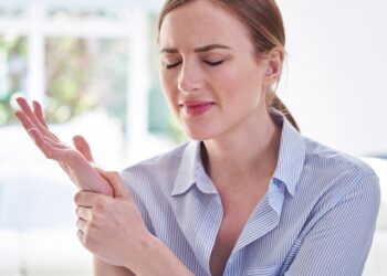 Frau mit schmerzverzerrtem Gesicht hält ihr Handgelenk