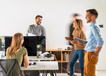 Eine Gruppe junger Menschen arbeitet im Stehen im Büro.