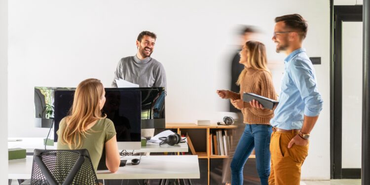 Eine Gruppe junger Menschen arbeitet im Stehen im Büro.