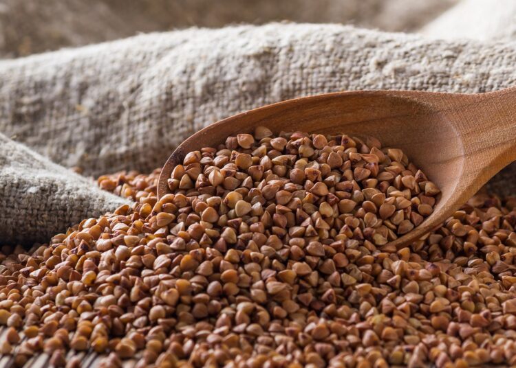 Buchweizen und ein Holzlöffel in einem Leinensack