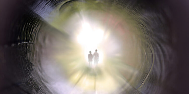 Das Bild zeigt zwei Menschen im hellen Licht am Ende eines Tunnels.
