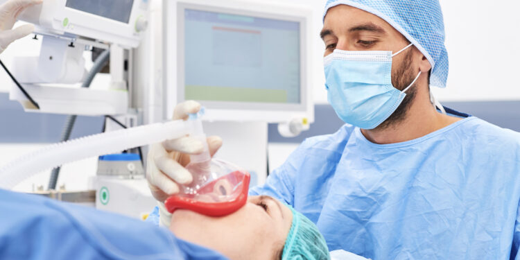 Das Bild zeigt einen Anästhesist im OP, der eine Patientin gerade in Narkose versetzt.