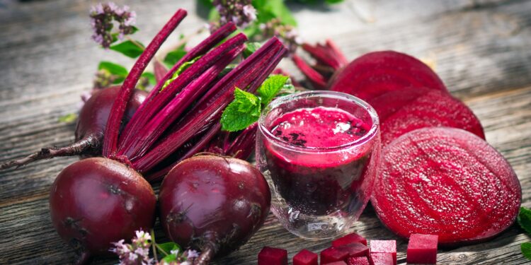 Rote Bete und Rote-Bete-Saft auf einer hölzernen Oberfläche.