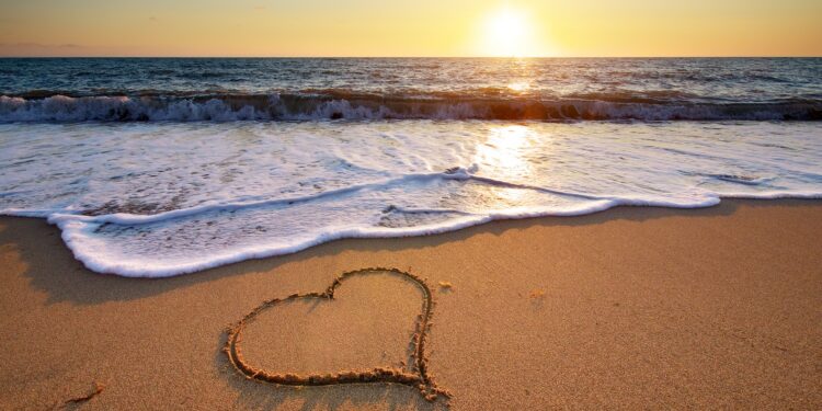 Ein Herz ist in den Sand an einem Strand gemalt.