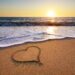 Ein Herz ist in den Sand an einem Strand gemalt.