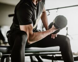 Ein Mann trainiert seinen Bizeps mit Hanteln in einem Fitnessstudio.
