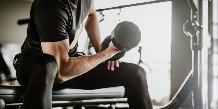 Ein Mann trainiert seinen Bizeps mit Hanteln in einem Fitnessstudio.