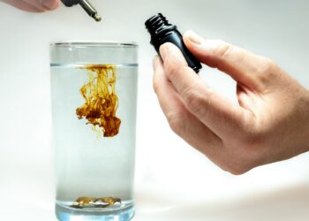 Ein Tropfen kolloidales Silber wird in ein Glas voll Wasser geträufelt.