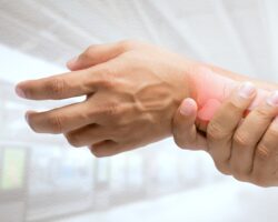 Eine Person greift sich an das Handgelenk.